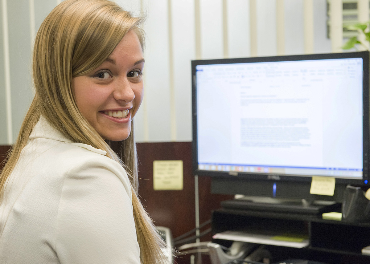 girl in front of computer smiling at camera