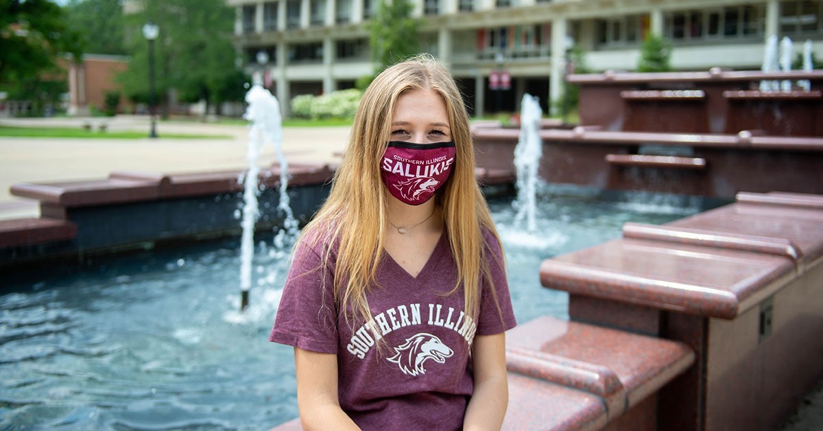 girls sitting in front of a fountain wearing a mask