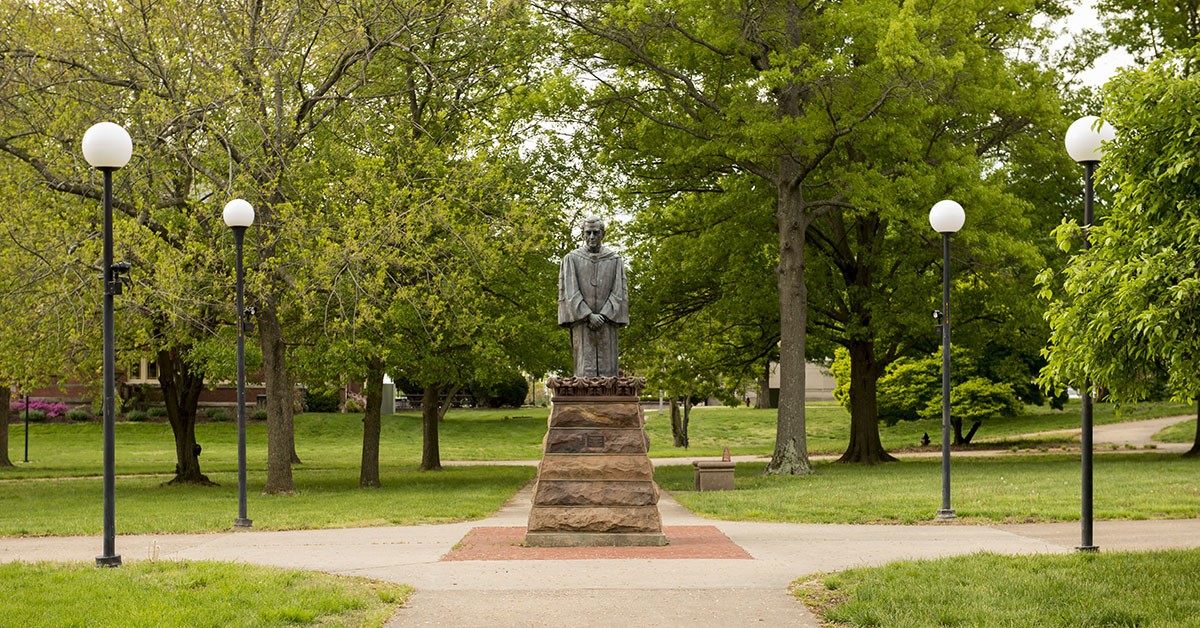 stone statue surrounded by green grass and trees