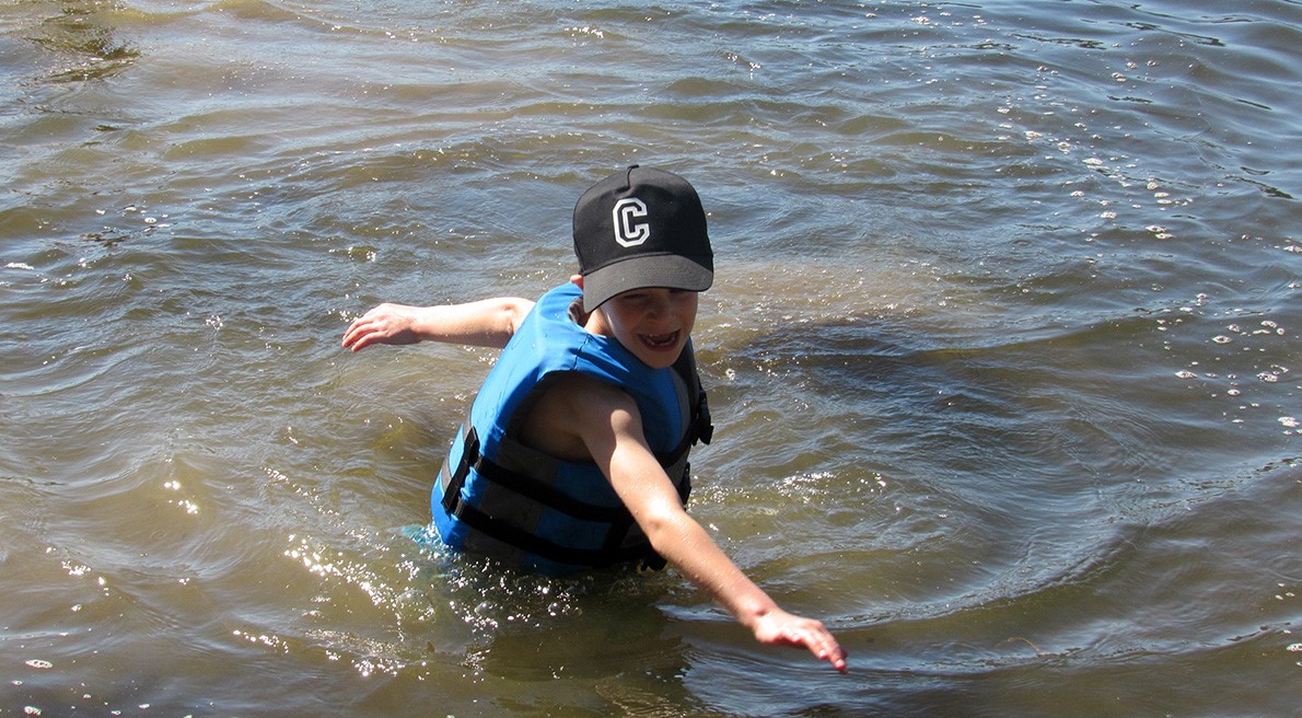 child wearing a hat, playing in the water