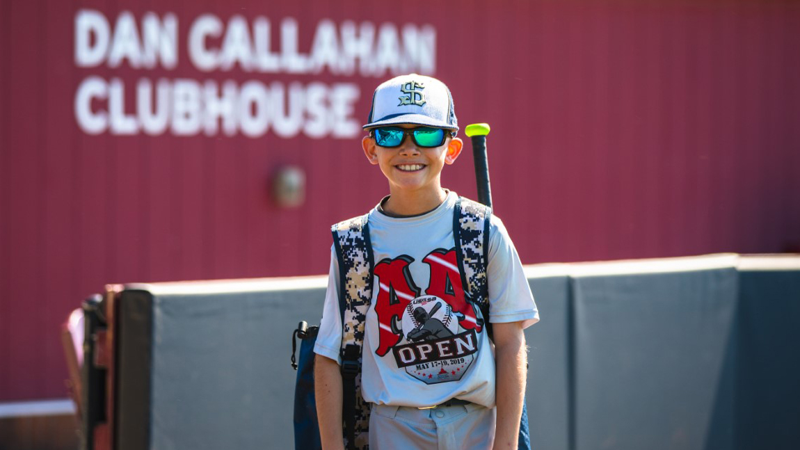 young boy wearing sunglasses, baseball cap, smiling