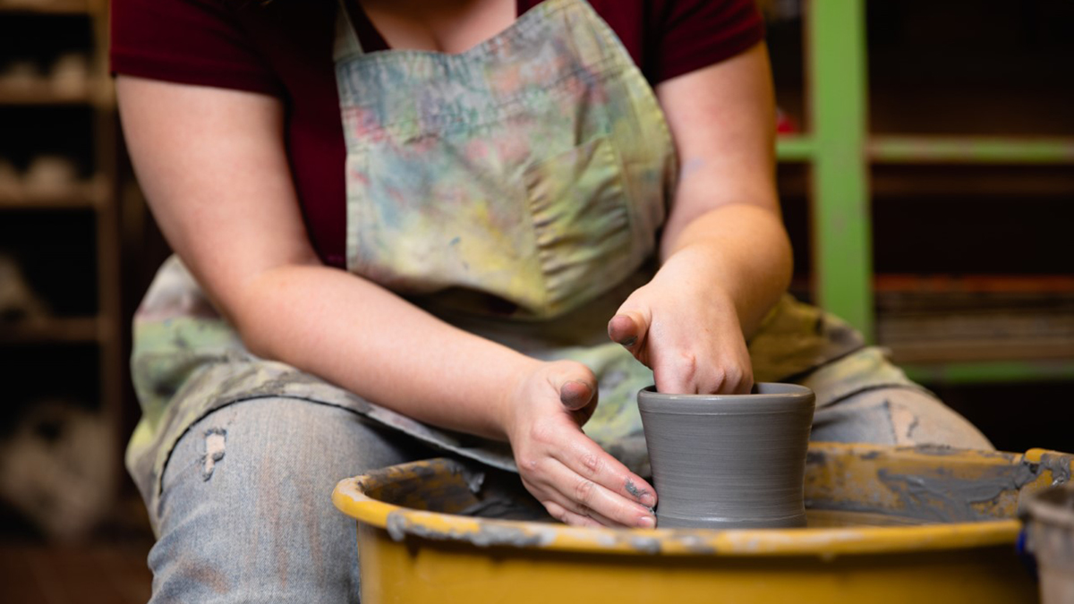 female working clay on a potters wheel