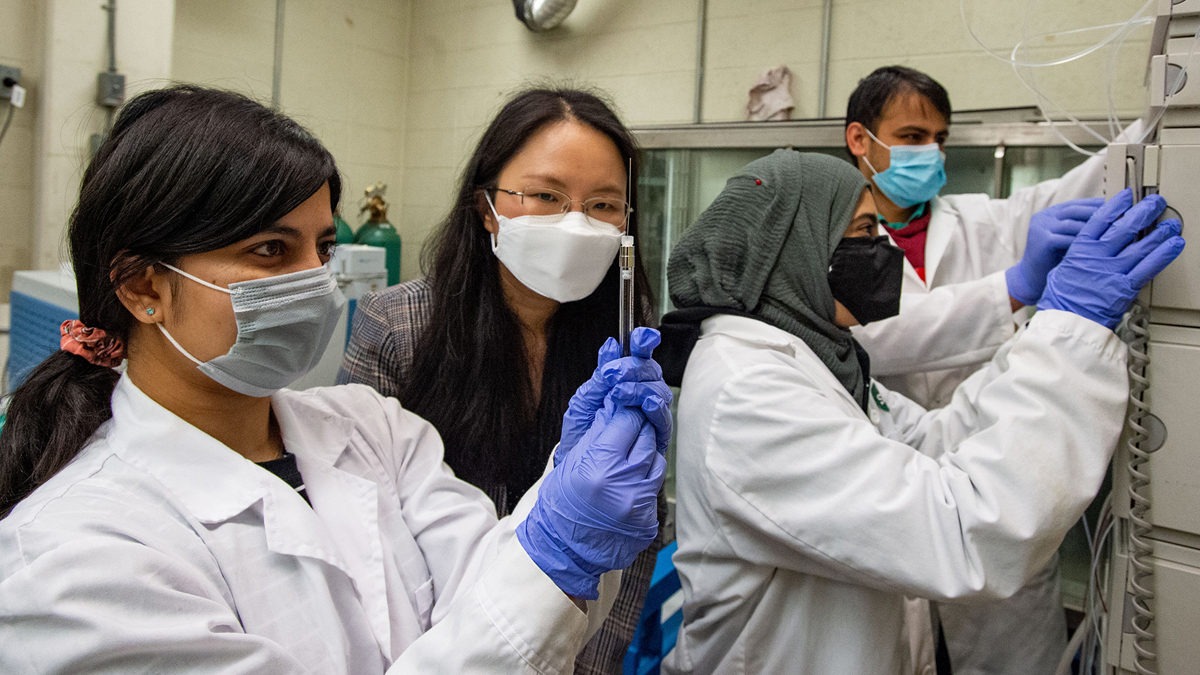 people in a lab wearing lab coats and masks