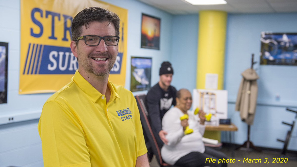 Phil Anton, smiling, while people do physical therapy in the background