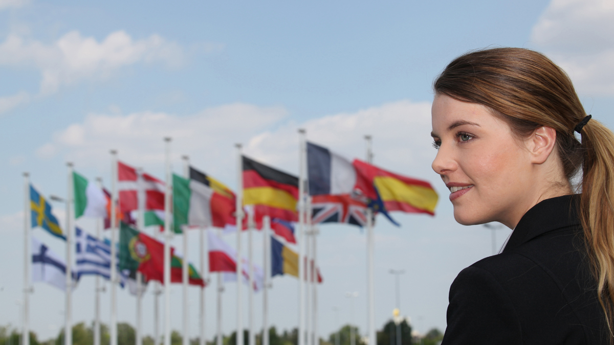 young woman with many nations flags waving in the background