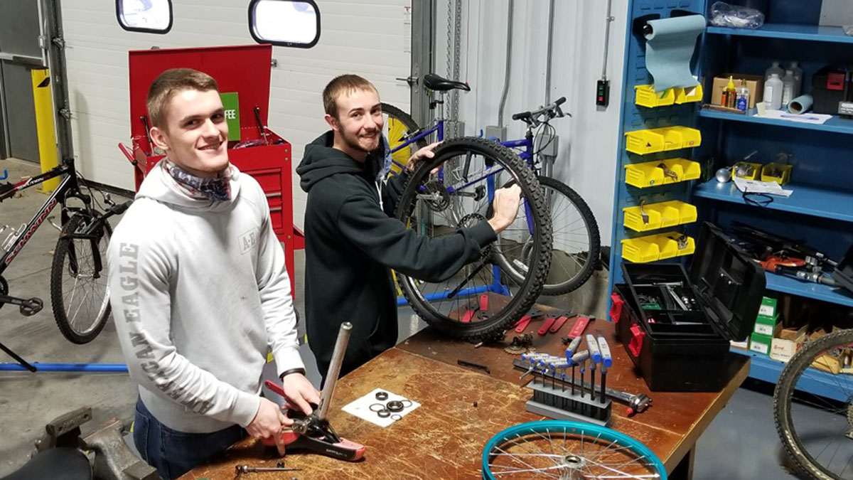 two young men repairing bicycles
