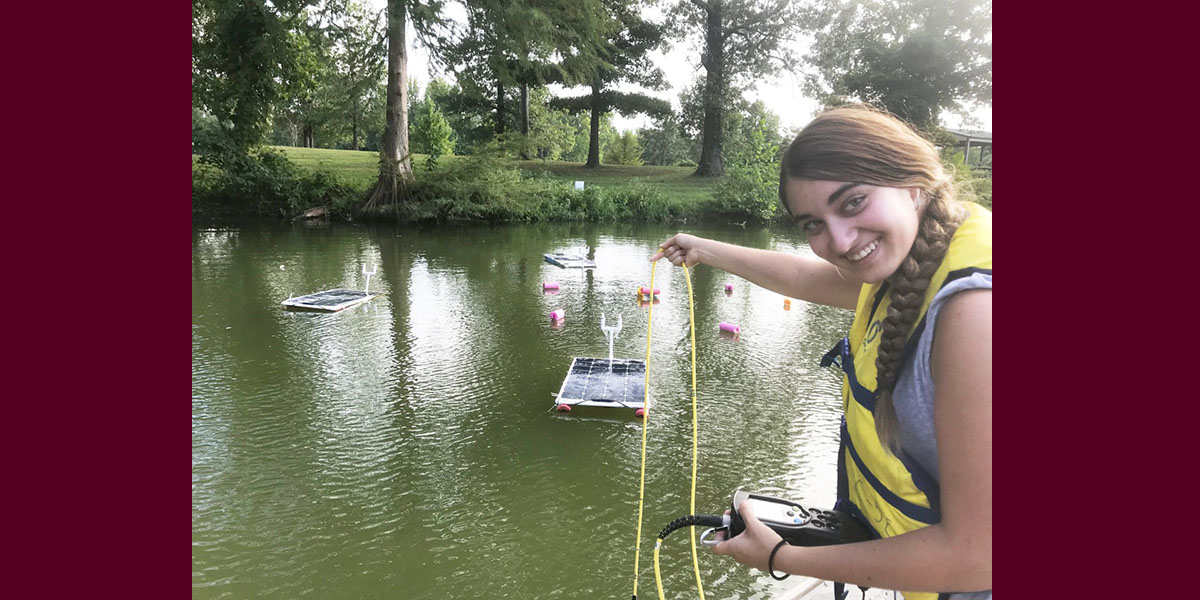 student installing solar powered fountains in Campus Lake