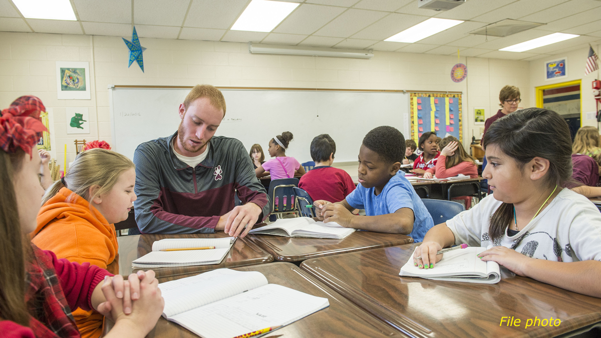 young man tutoring young children