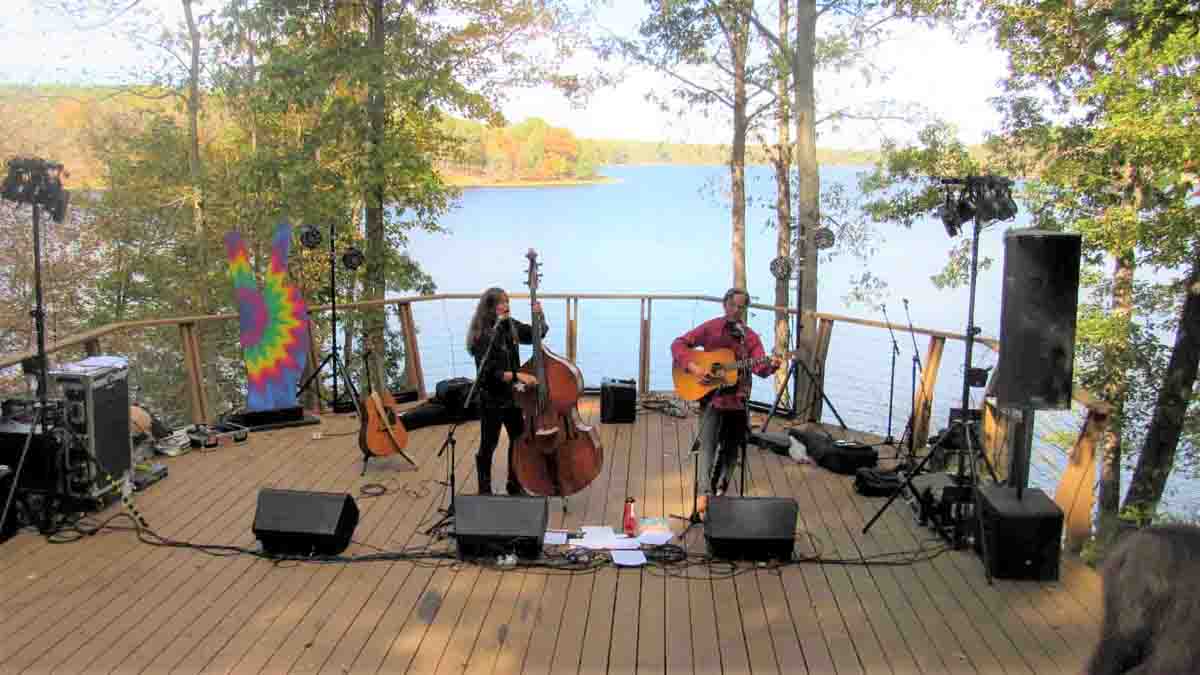 two people singing on a stage with water in the background