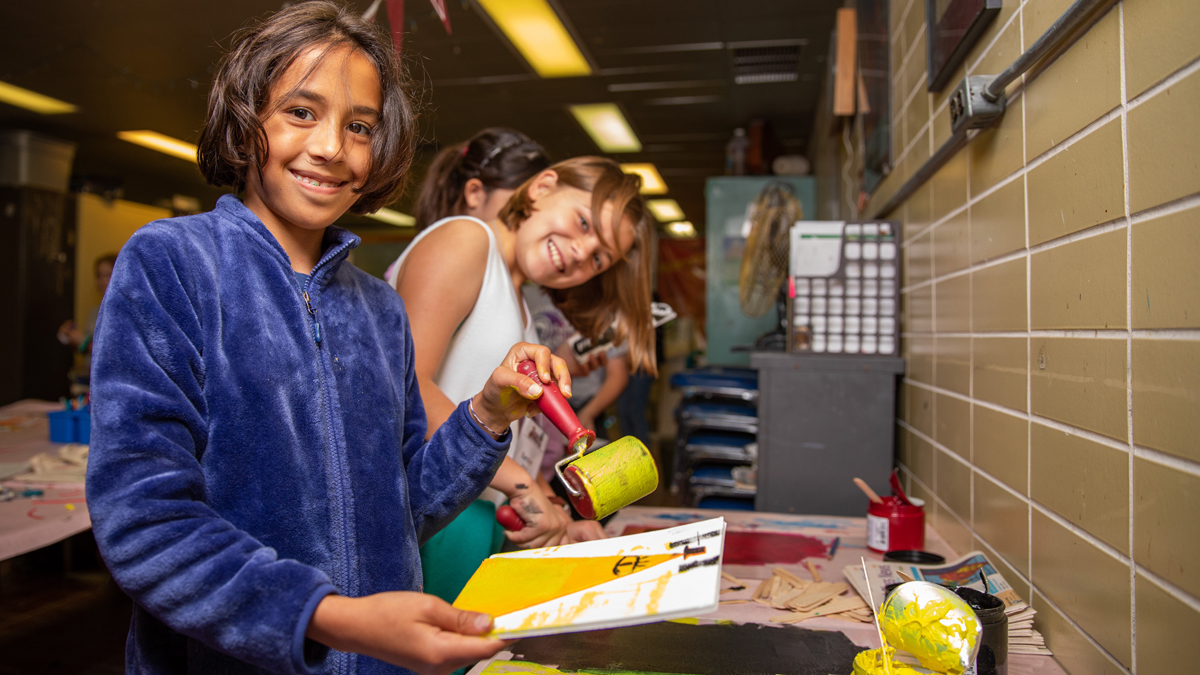 children smiling at the camera while working on art