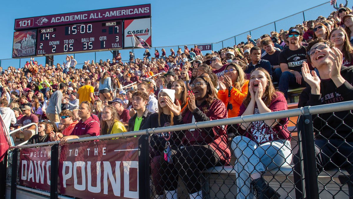 Fans cheering in the student section at an SIU football game.