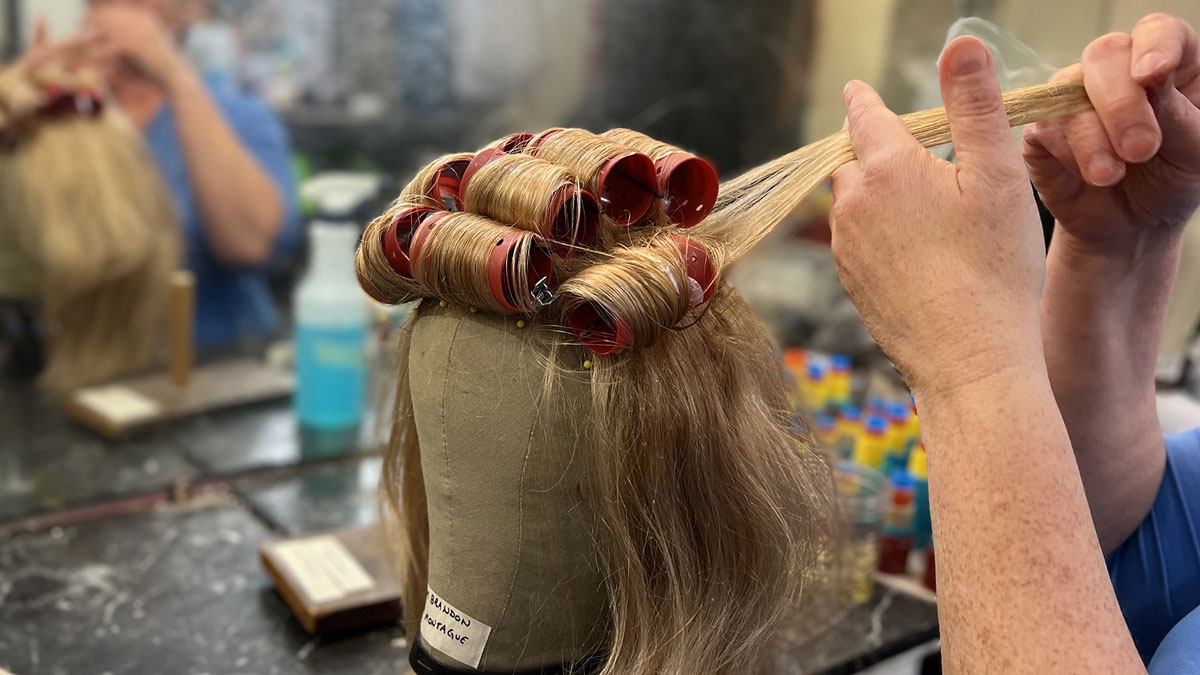 Hands are preparing a wig for styling. 