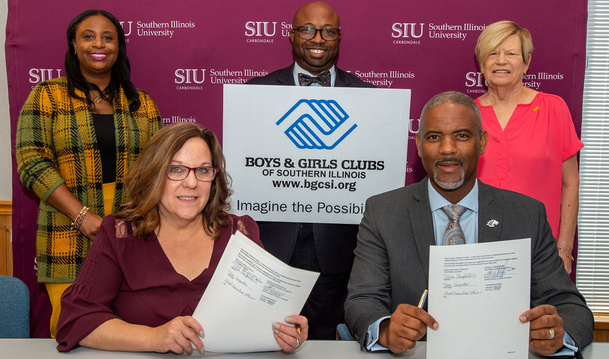 Representatives of SIU and the Boys and Girls Clubs of Southern Illinois are seen seated and standing, displaying newly signed documents.