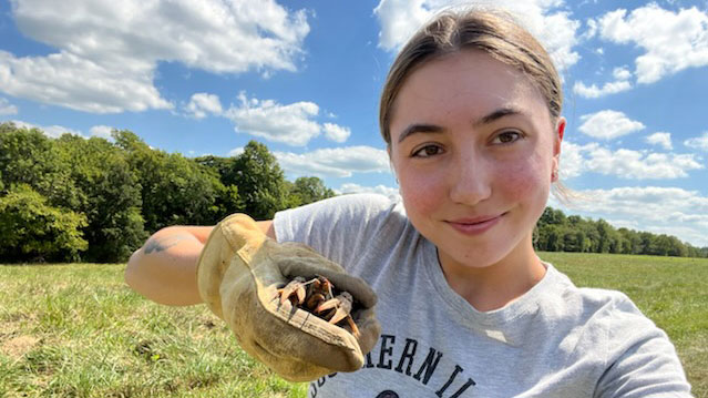 young woman holding a crayfish and smiling.