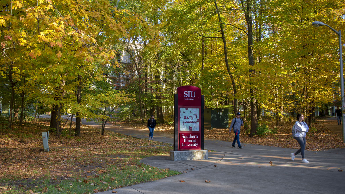 Students walking on campus. Fall has arrived and the leaves are various shades of orange, gold and brown.