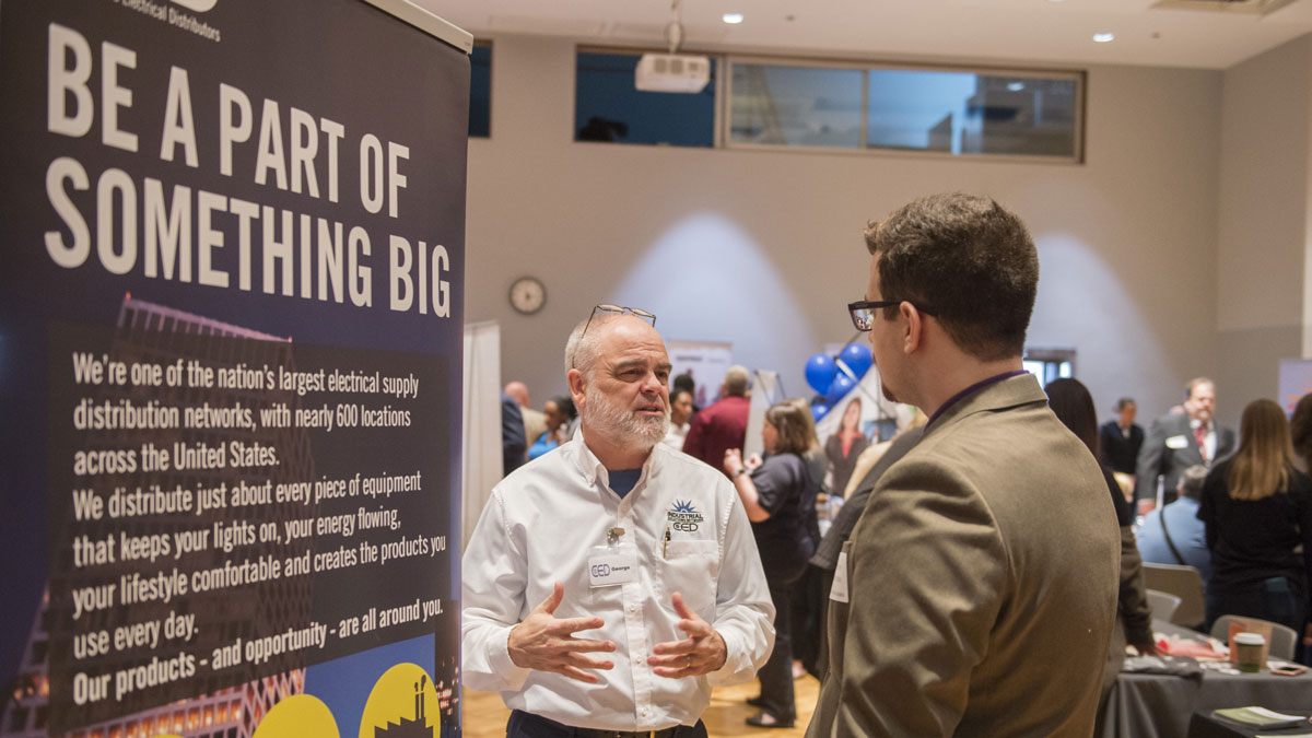 Students speaking with potential employers at a job fair