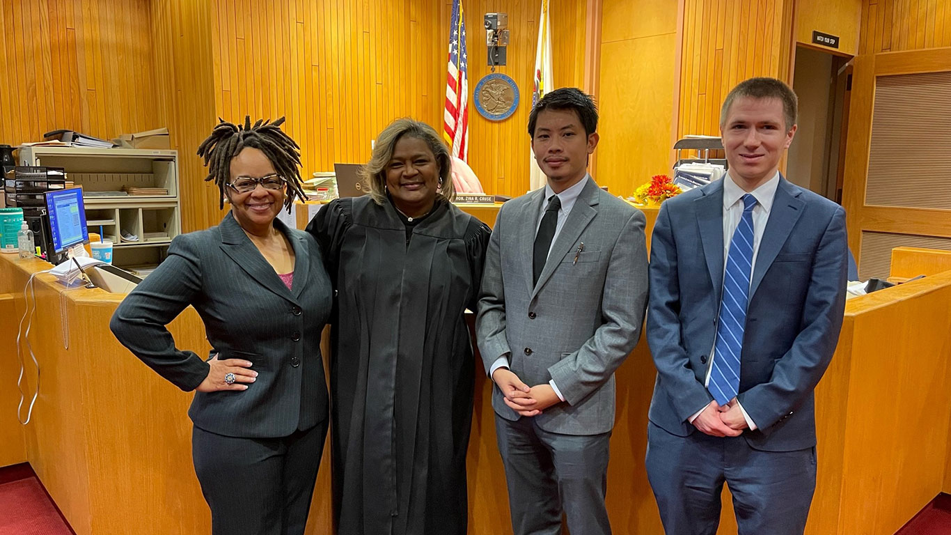 law students stand, smiling with a judge