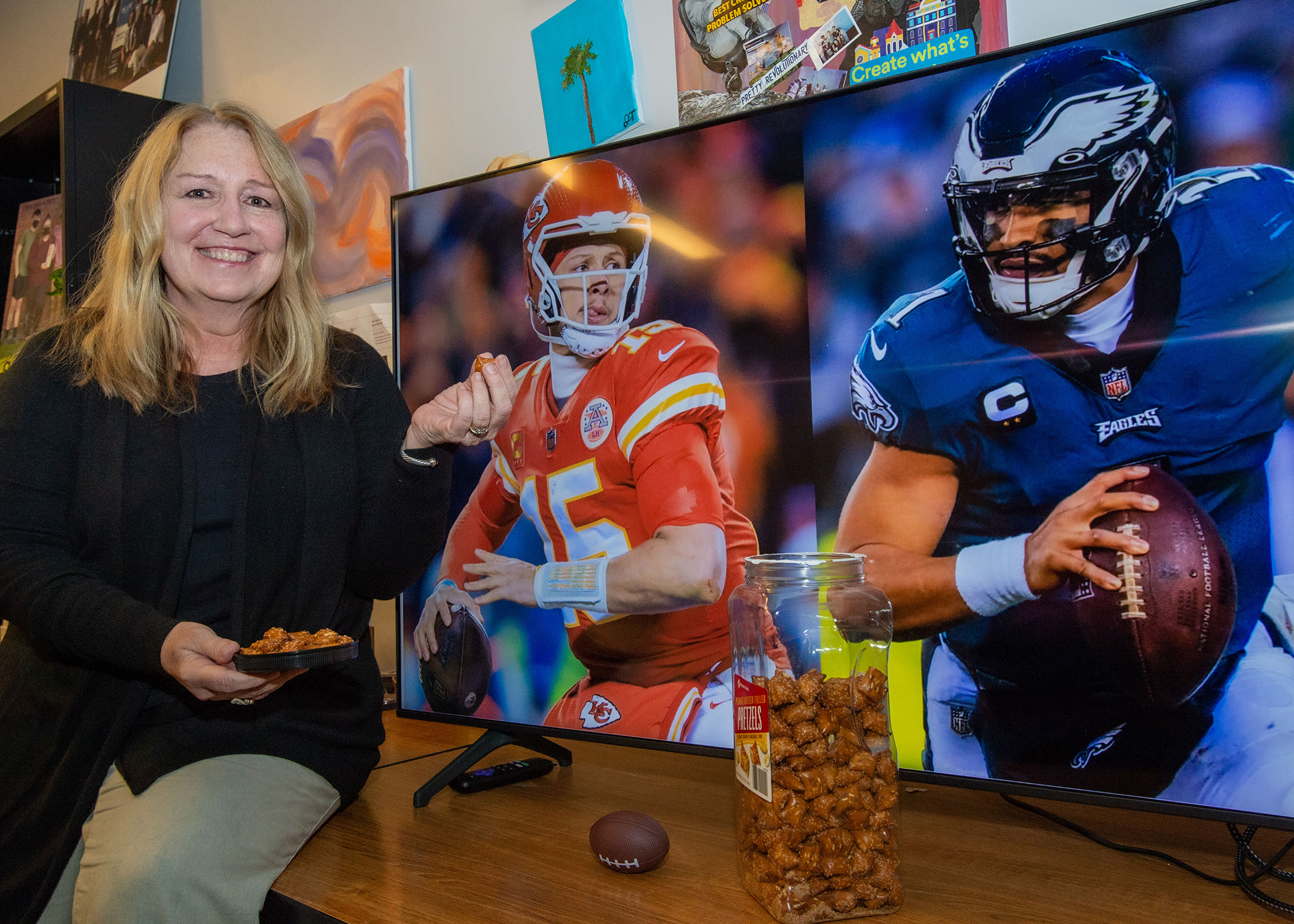 Bridget Lescelius sits in front of a TV displaying Super Bowl ads