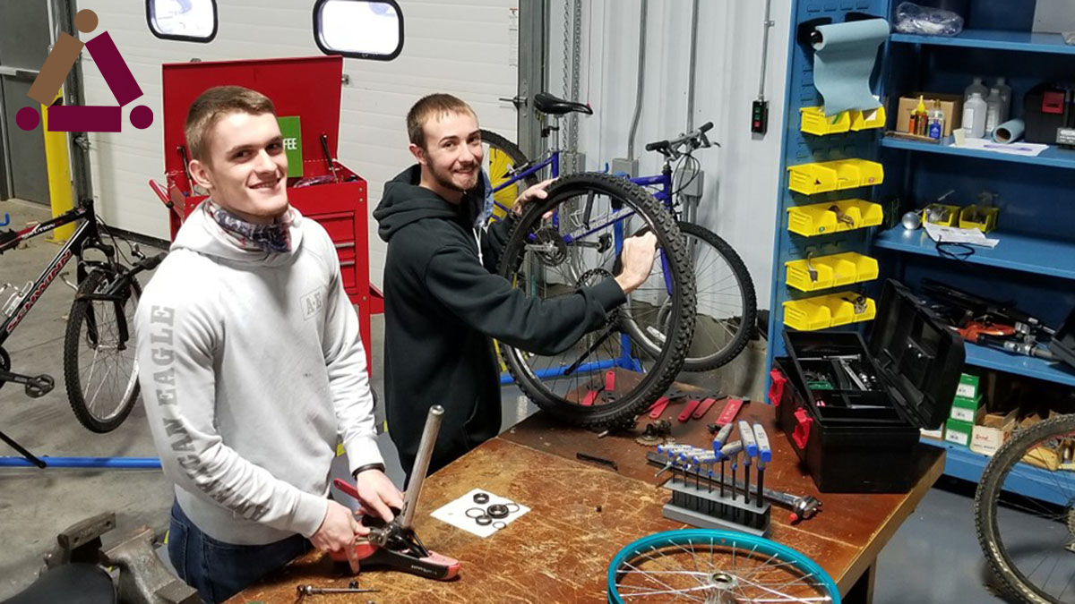 two young men are repairing bicycles