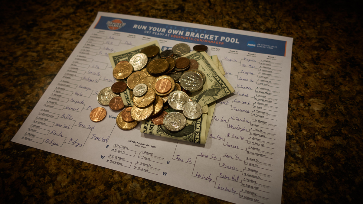 money piled on a basketball bracket sheet