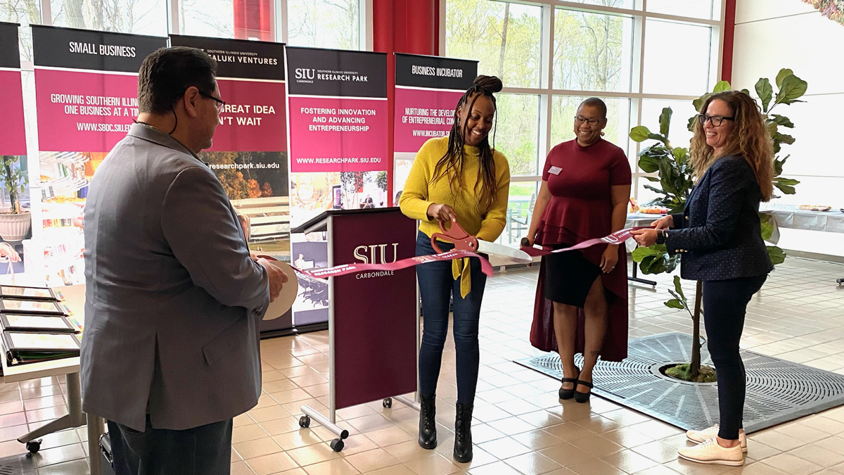 Candace Monae of K2 Academy cuts the ribbon to celebrate the creation of her business and her graduation from the SBDC’s Launch That Business program. SBDC officials hold the ribbon and join her in marking the special occasion.  