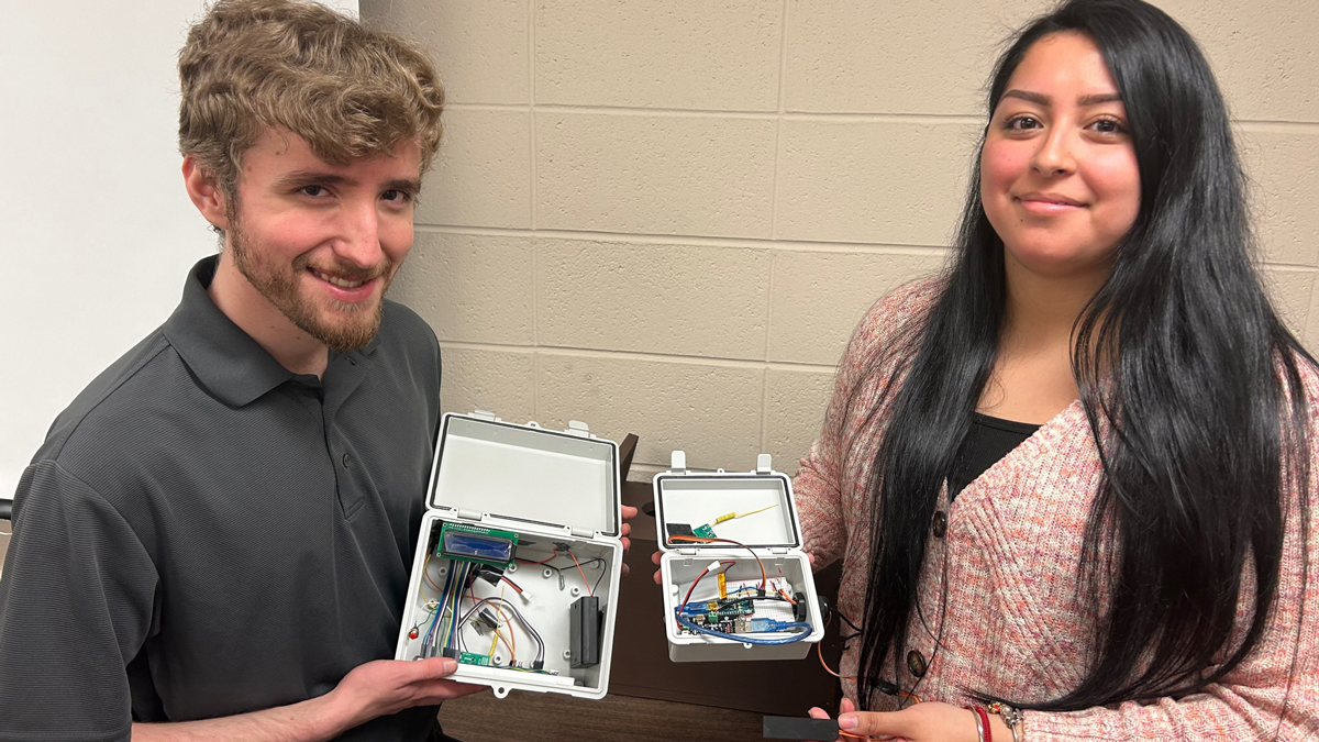 SIU electrical engineering technology graduates hold the transmitter and receiver for a new system they developed to help a Central Illinois conservation group monitor kestrel nesting boxes.