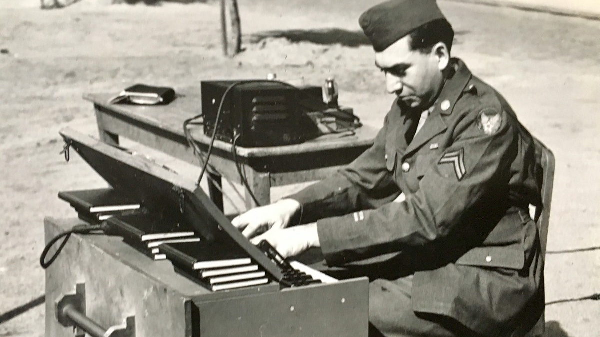 American composer Lionel Semiatin creates music, seated at an organ, on the beach at Normandy during World War II