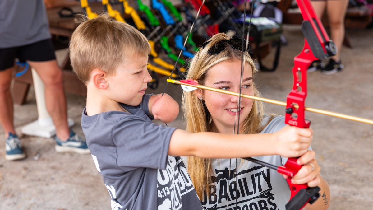 SIU student helps a participant with archery.