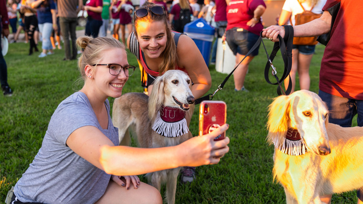 A young woman is seen taking a selfie with a Saluki