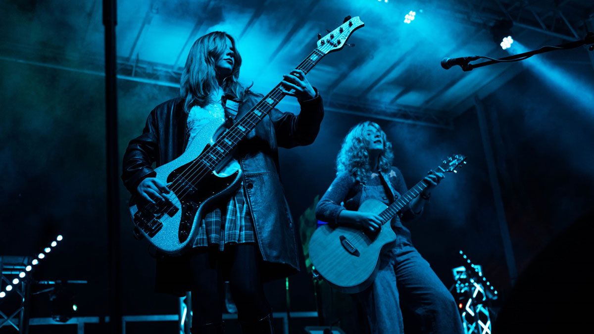 A band performs on stage, illuminated by blue light.