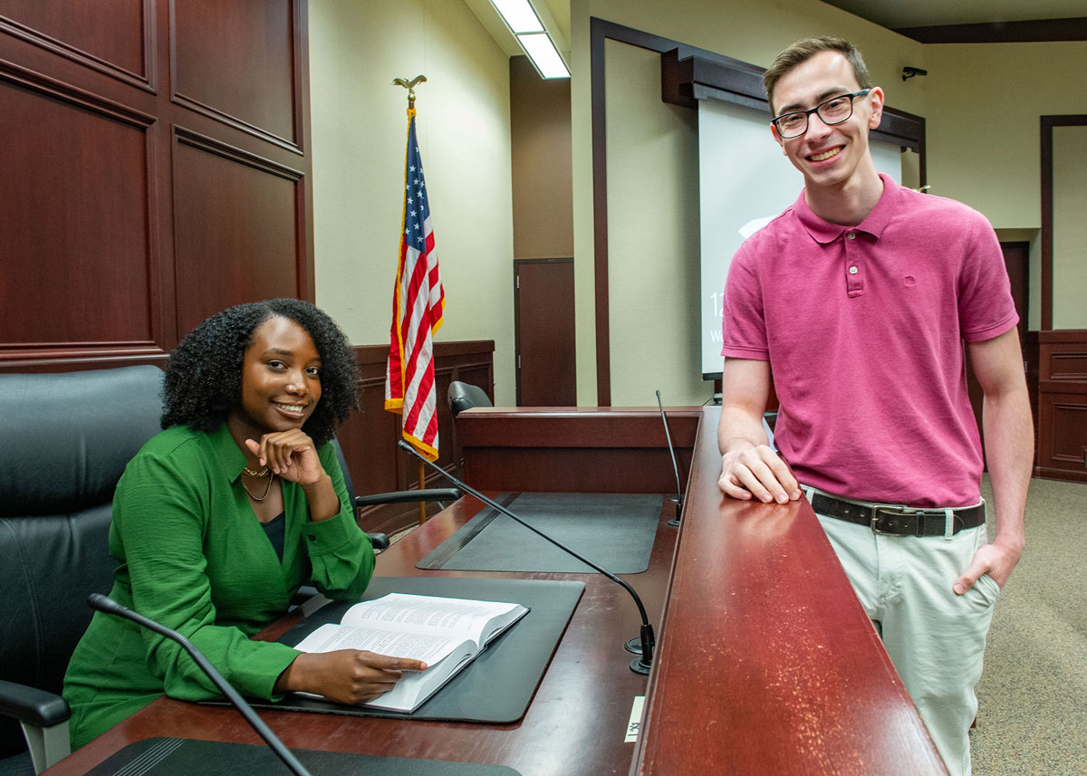 A young black woman and young white man are seen standing in a law school courtroom