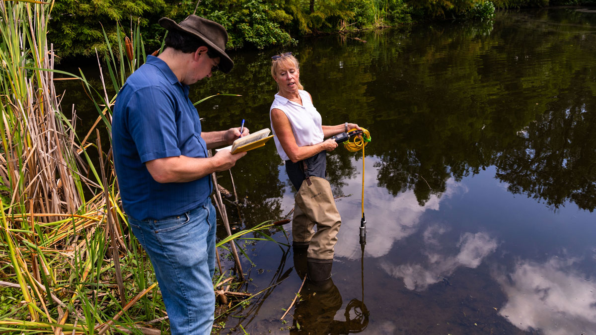  A man and woman are seen taking measurements in a lake