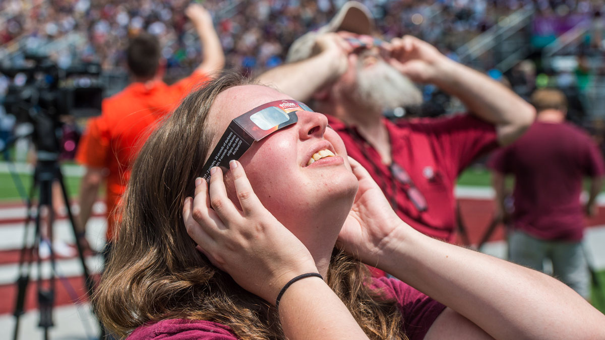 Woman wearing eclipse glasses, looking up to the sky
