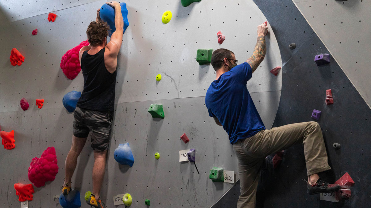 Two people climbing an indoor climbing wall