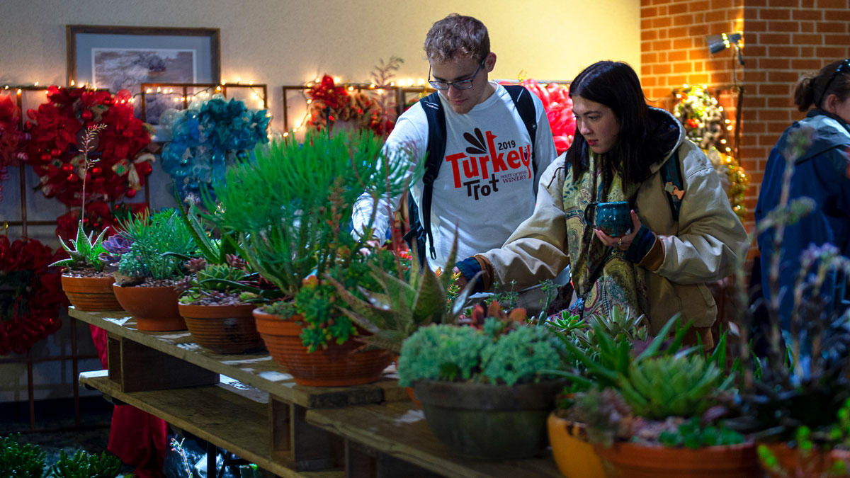 People at a craft sale perusing a table filled with various plants