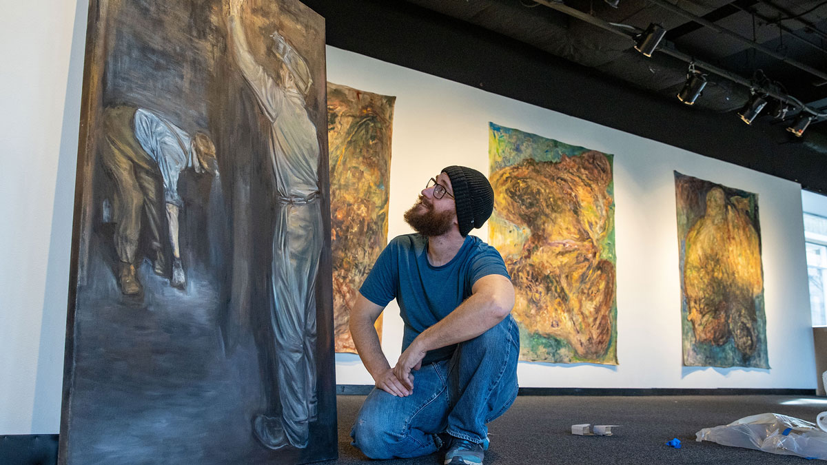 a man kneels in front of a painting