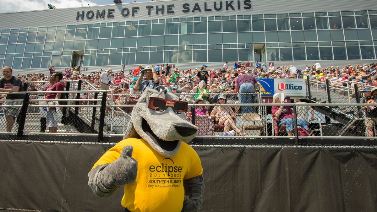 Grey Dawg is giving a thumbs up while at Saluki Stadium. 