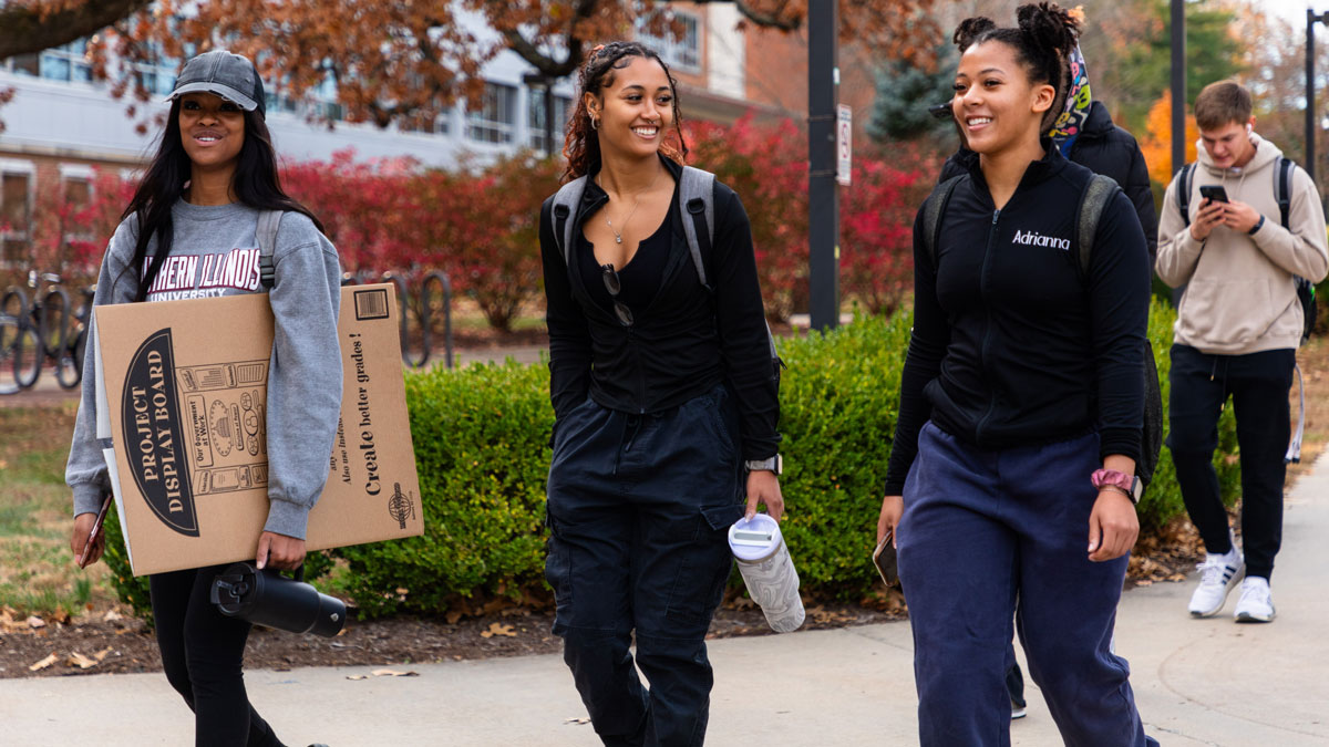 Three young black women are walking on campus.