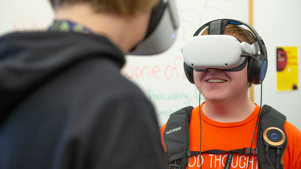 A young man is smiling while wearing a VR headset.