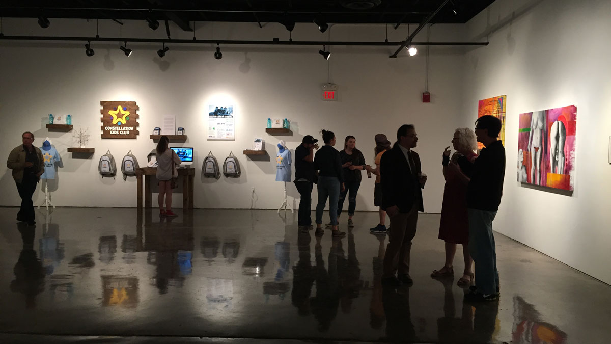 People are seen milling about in an art gallery.