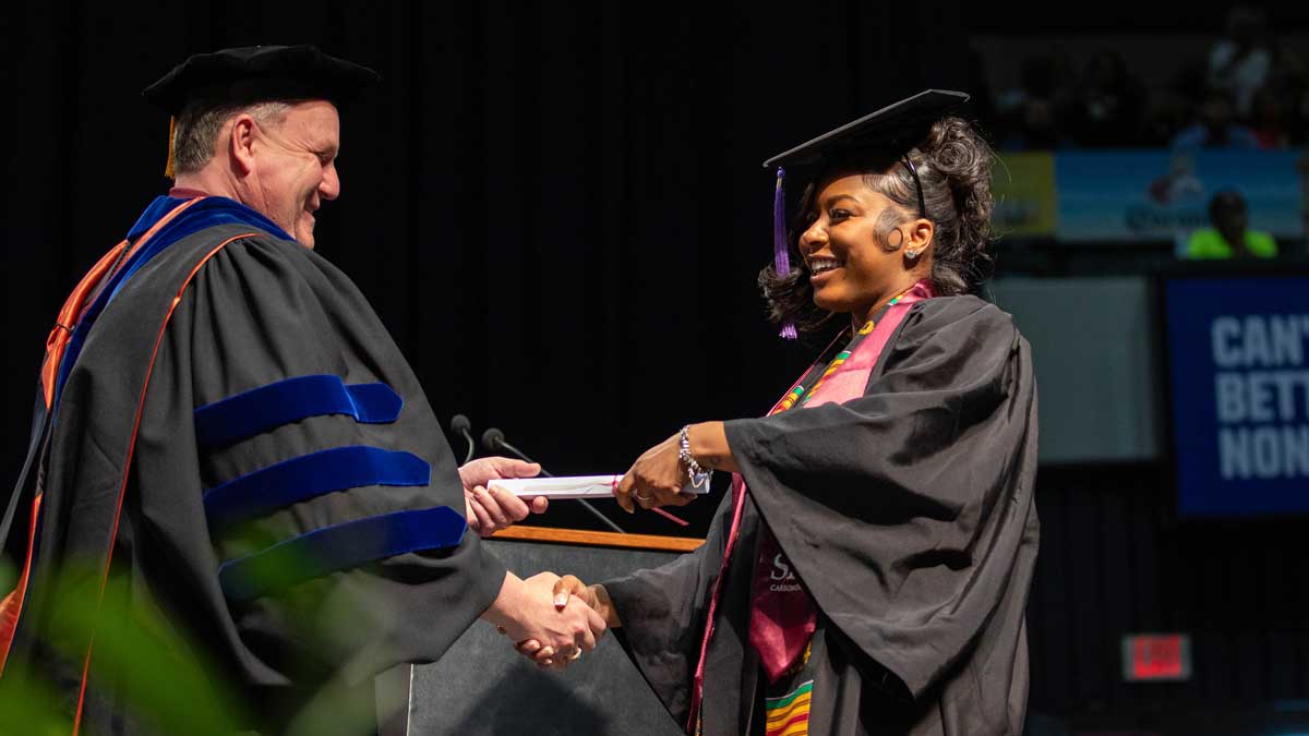 A black woman is receiving her diploma from college. 