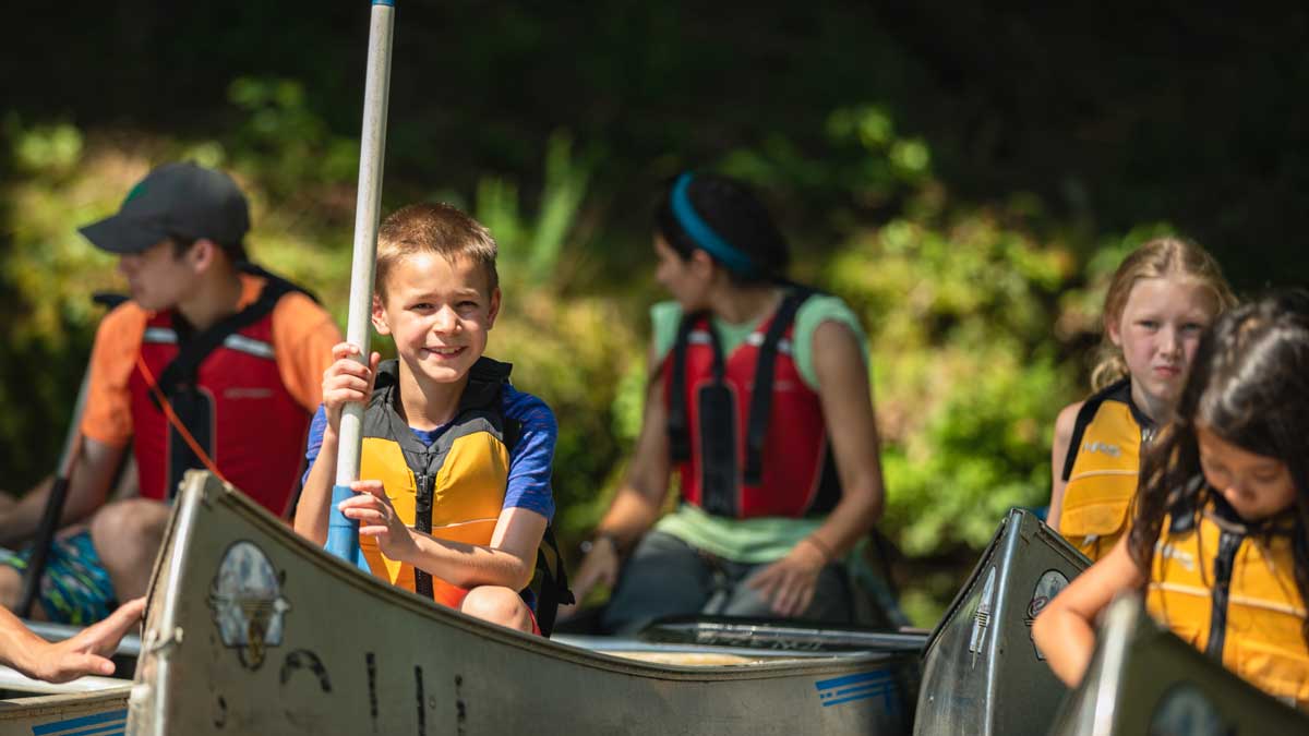 Image of children in canoes, wearing life jackets