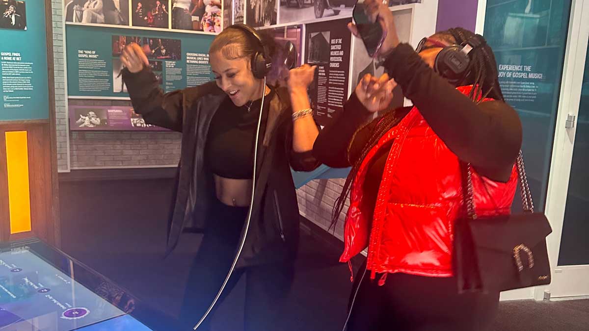 Two young, black women are dancing while listening to music
