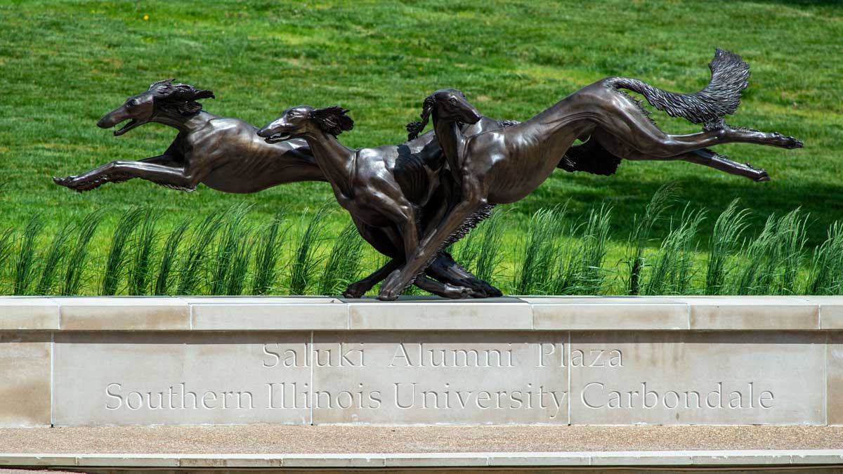 Image is a sculpture of three Salukis, in various stages of running. 