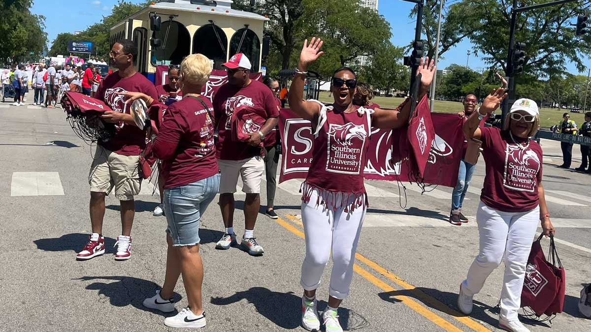 SIU alumni member are wearing maroon while walking in a parade