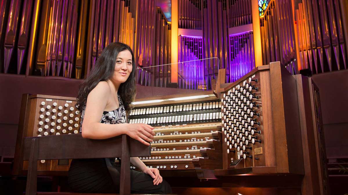 A woman is seated in front of an elaborate organ