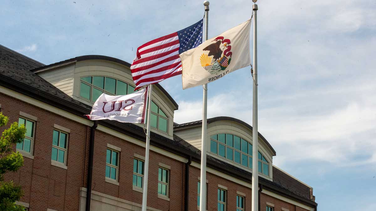 Three flags are waving. The US flag, the Illinois state flag and the SIU flag