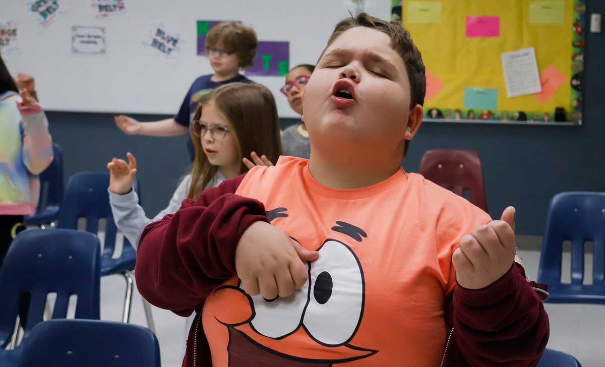 A group of children are singing in a classroom