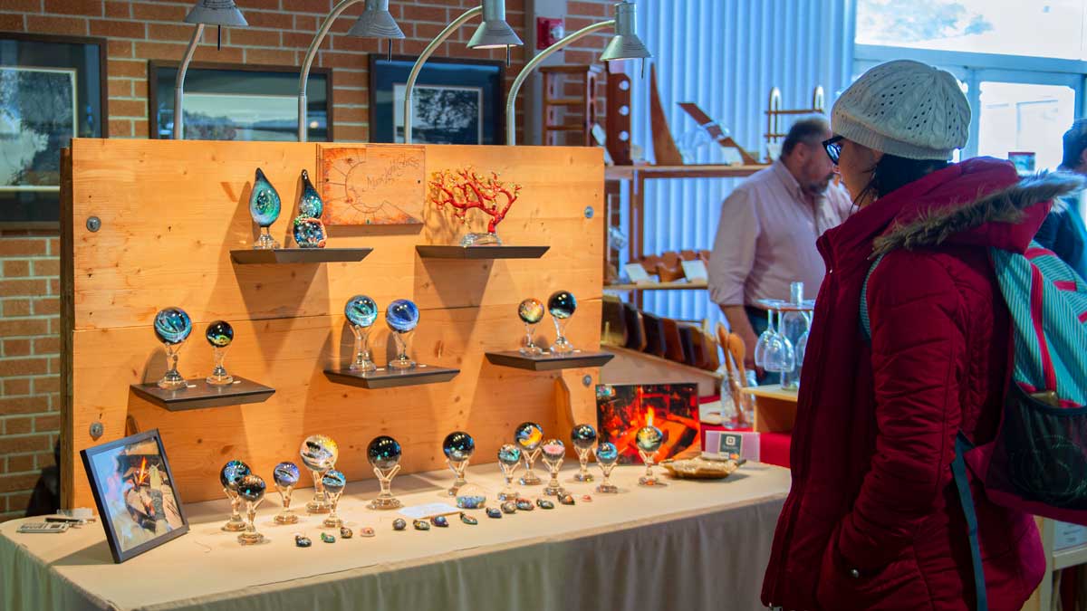 A woman is looking at glass orbs at a craft show.