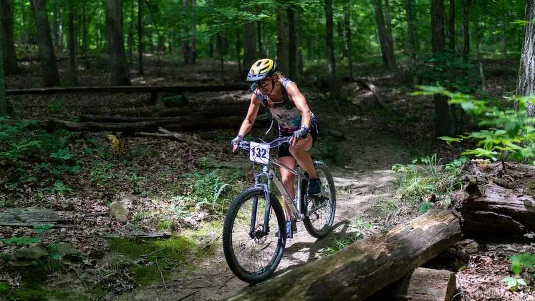 A person rides a bike through a wooded area